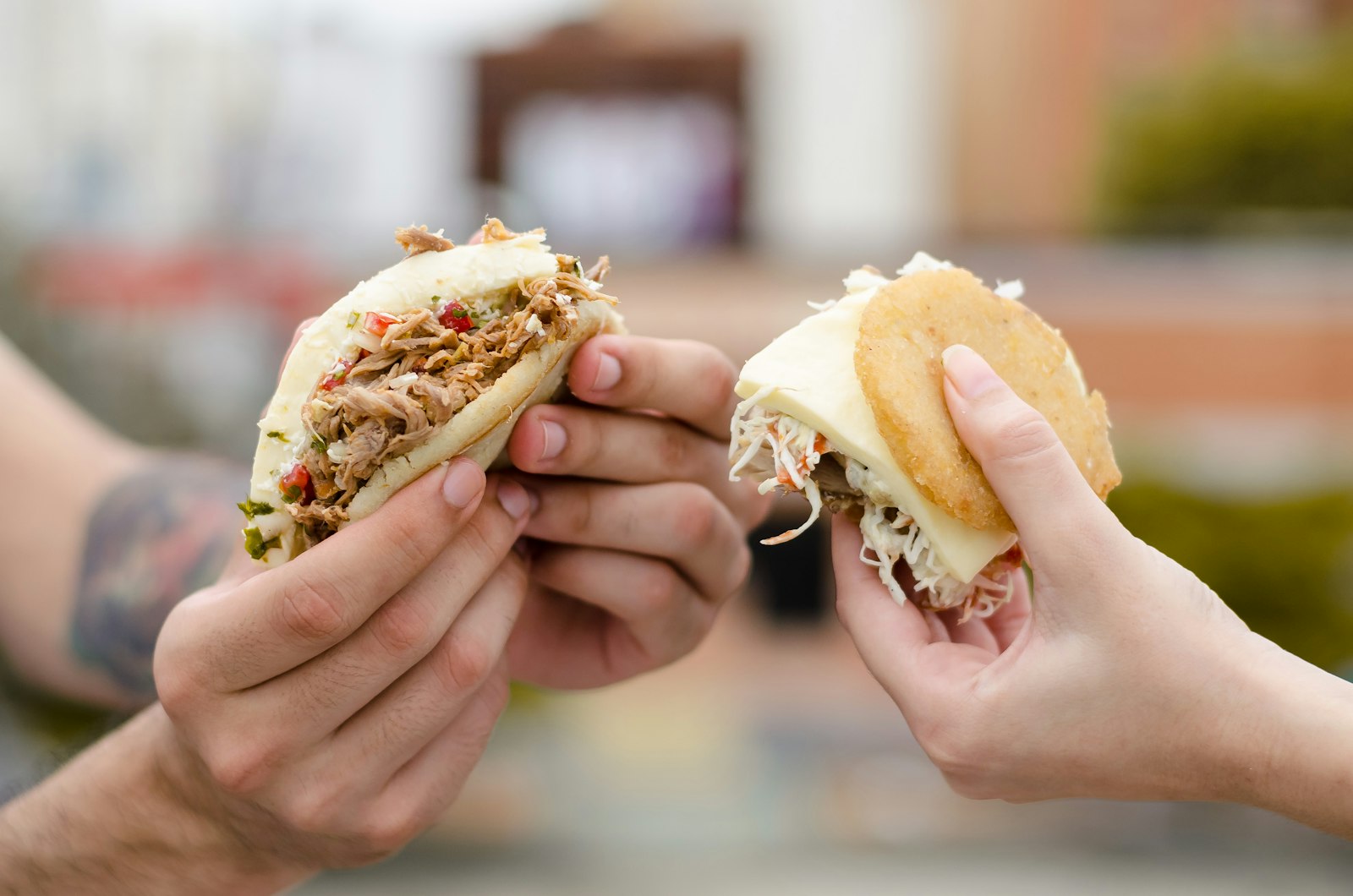 Mano sosteniendo una arepa rellena de queso recién hecha