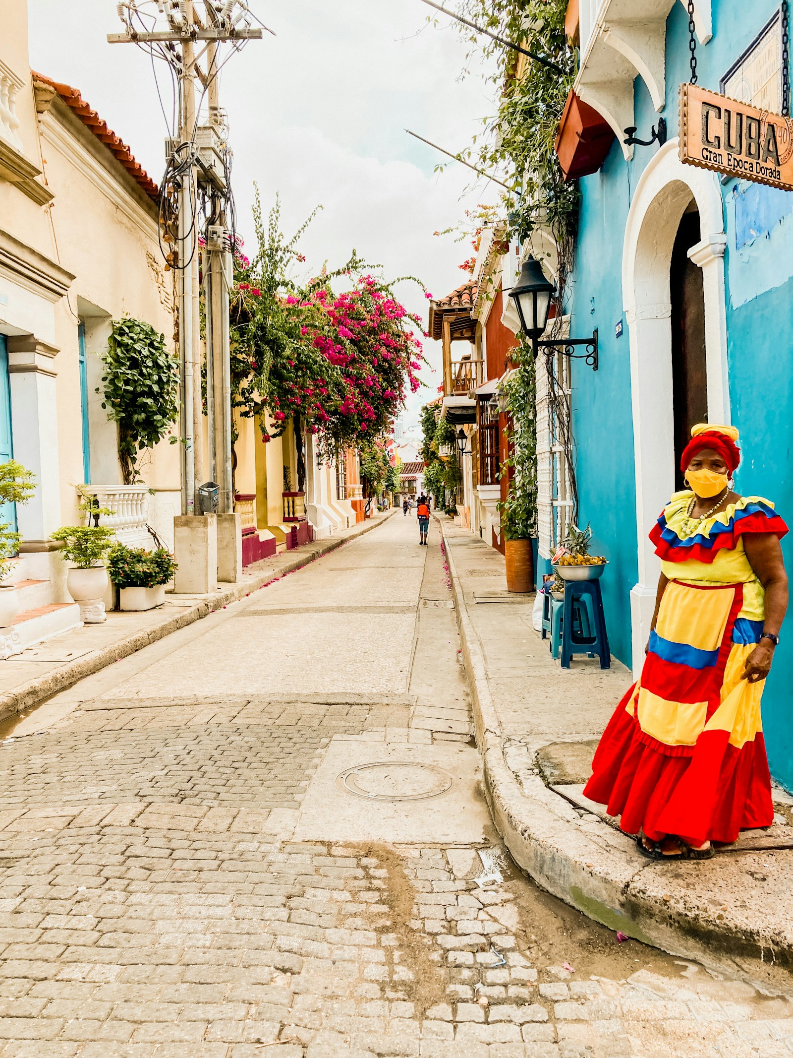 Palenquera con vestido de colores en una calle empedrada de Cartagena de Indias