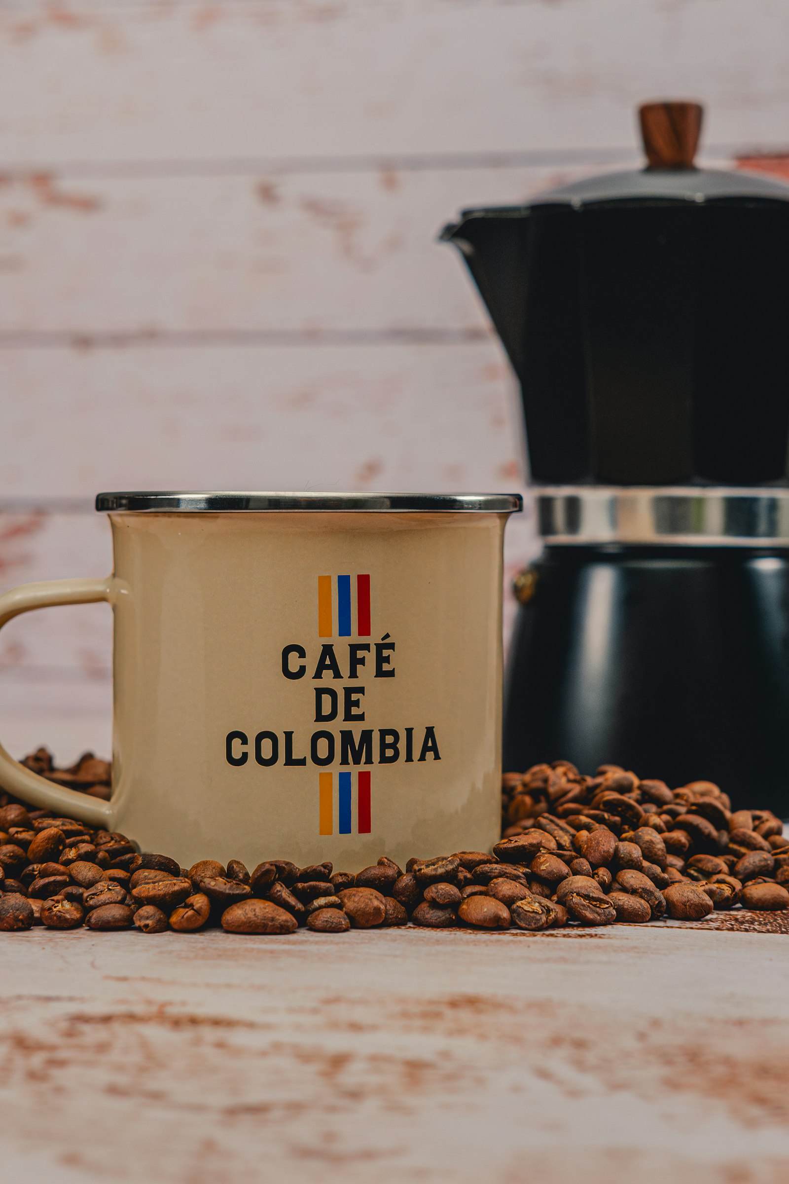 Taza de café colombiano con granos tostados y una cafetera tipo moka