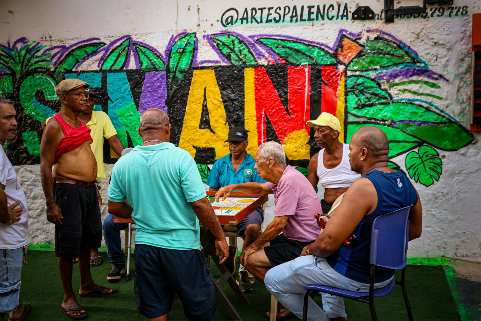 Vecinos jugando un juego de mesa frente a un mural colorido en Cartagena